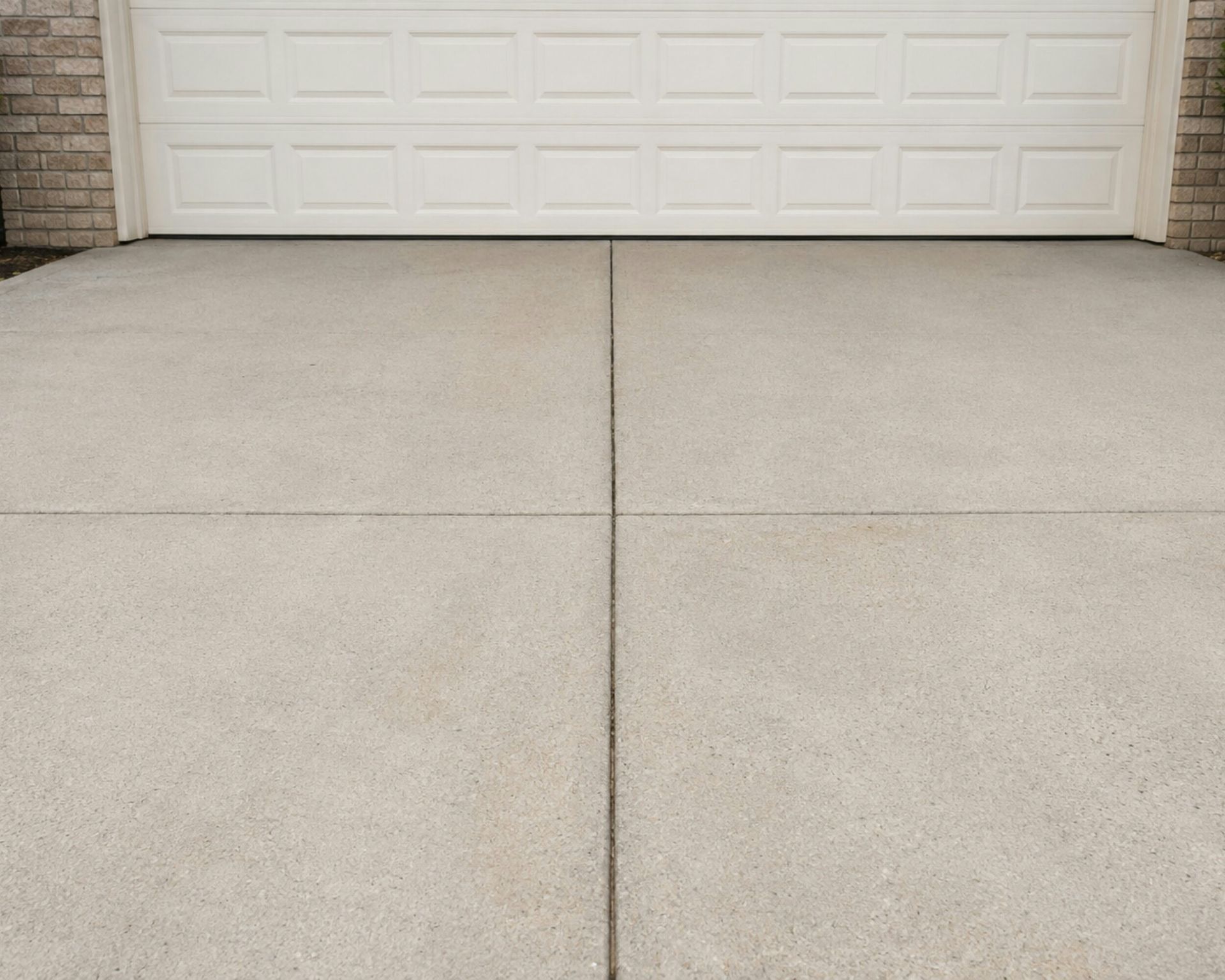 A concrete driveway in front of a white garage door.