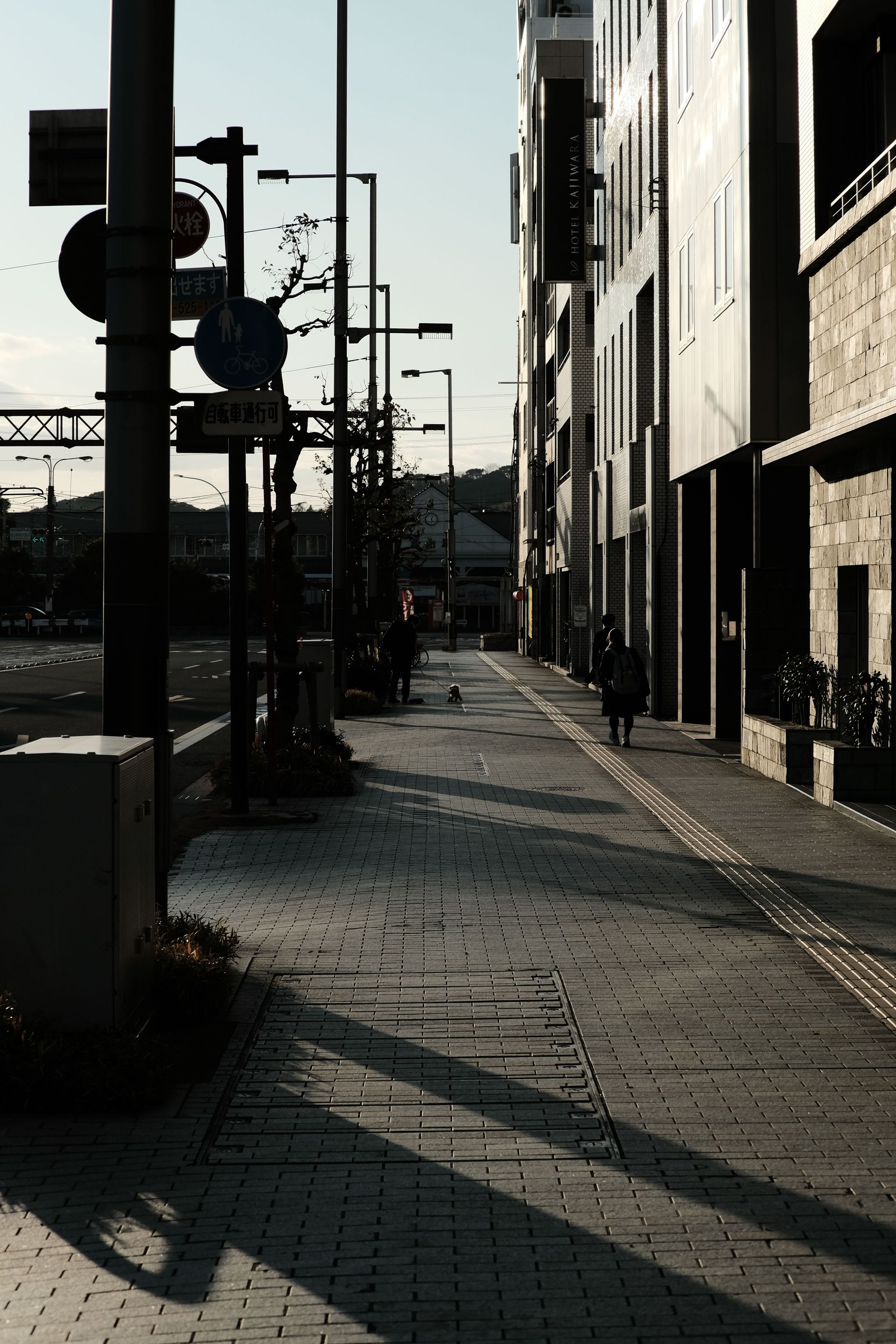 A quiet city street with modern architecture and long shadows at dawn.