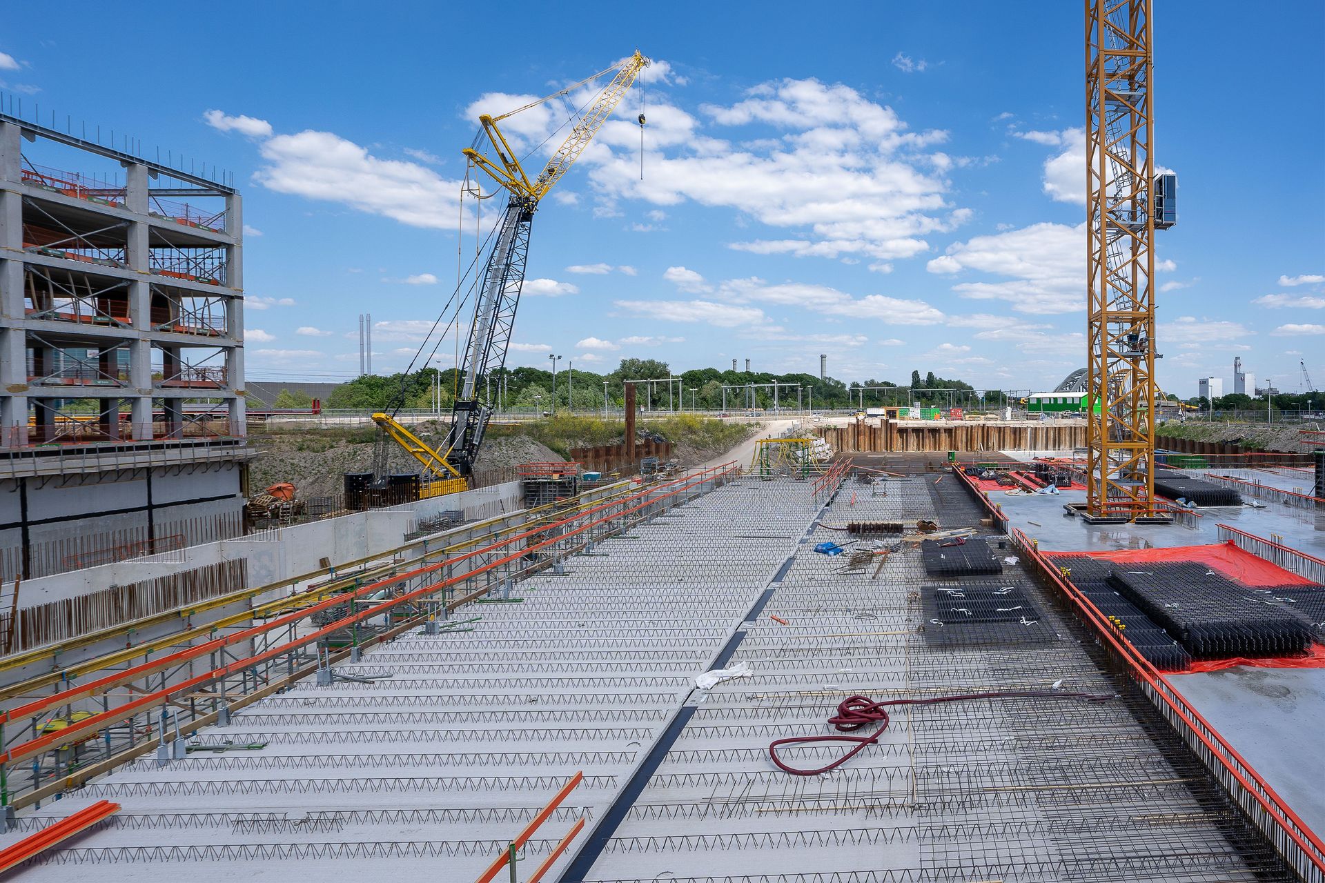 View of a busy construction site with cranes and building structure under clear sky.